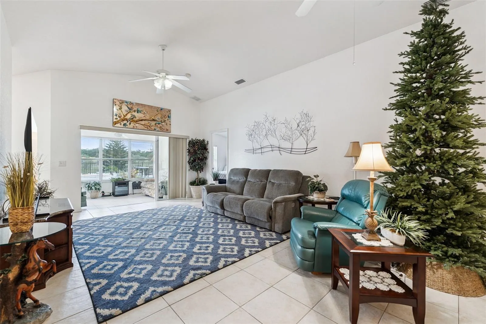 Spacious Great Room makes an immediate impression with its soaring vaulted ceiling and triple glass sliding doors that open directly into the Florida Room