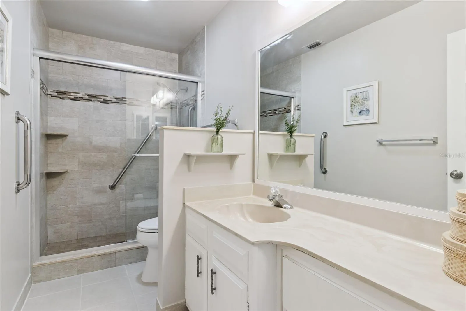Spacious en suite bath with wide marble vanity, multiple drawers and  ceramic tile flooring.