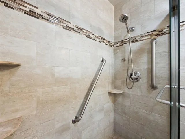 Stunning en suite, glass-enclosed shower with floor-to-ceiling and designer linear tiles plus built-in shelves.