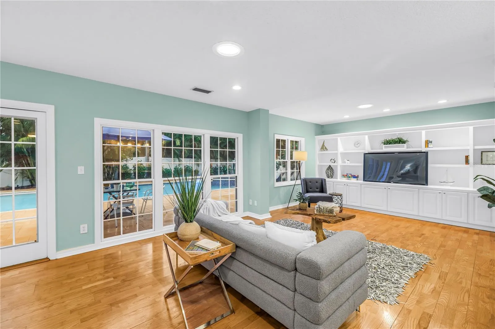 Spacious, casual living area adjacent to the kitchen, featuring direct views of the heated pool—an ideal setting for entertaining and watching the game with convenient access for a halftime swim.