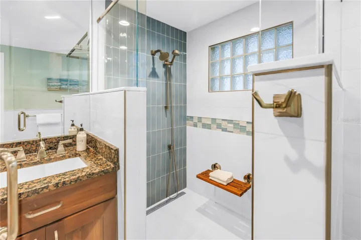 Exquisite spa-inspired walk-in shower featuring a built-in bench and a handheld shower wand.