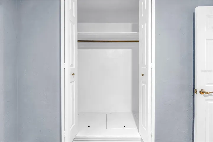 Third bedroom featuring a spacious closet with hidden floor-level storage.