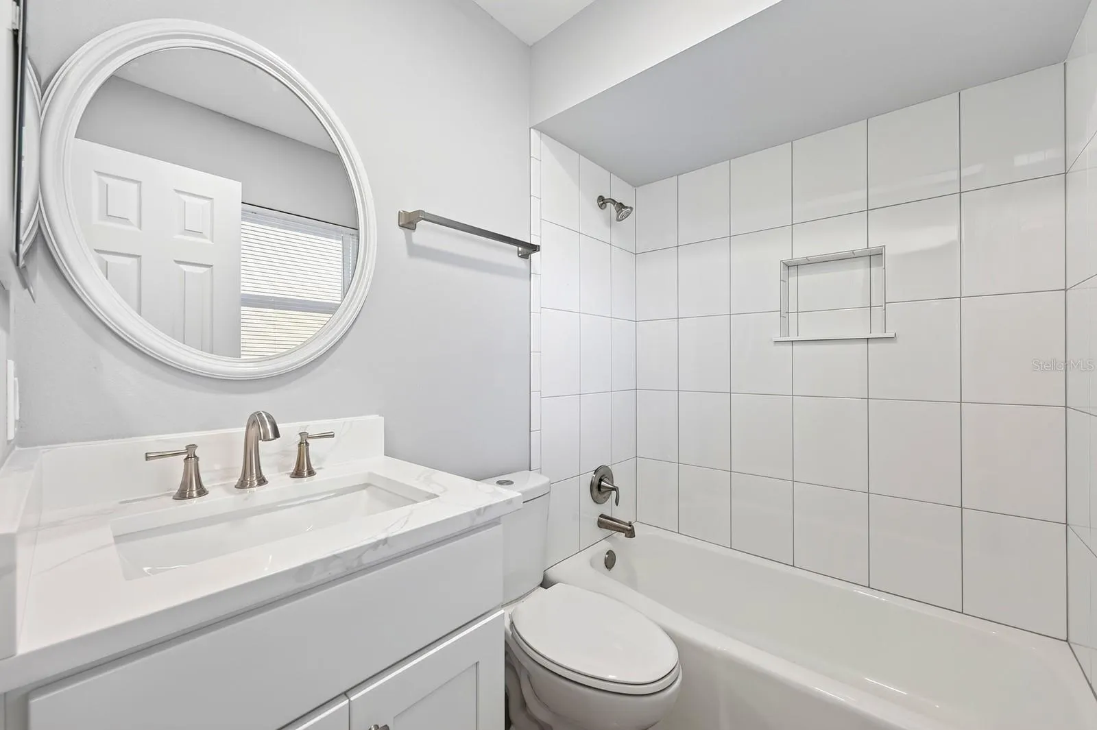 Private, en-suite bath with decorative mirror and fresh tile.