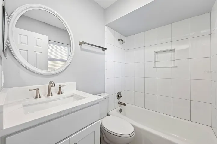 Private, en-suite bath with decorative mirror and fresh tile.