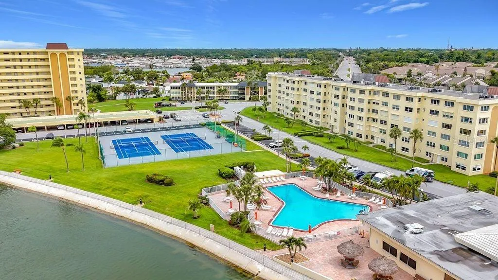 Resort-style community view featuring the Washington building, tennis and pickleball courts, and sparkling pool- all nestled around the tranquil bayou