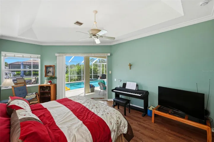 Sizable primary bedroom suite with alcove sitting area and sliders opening to the pool &amp; lanai.