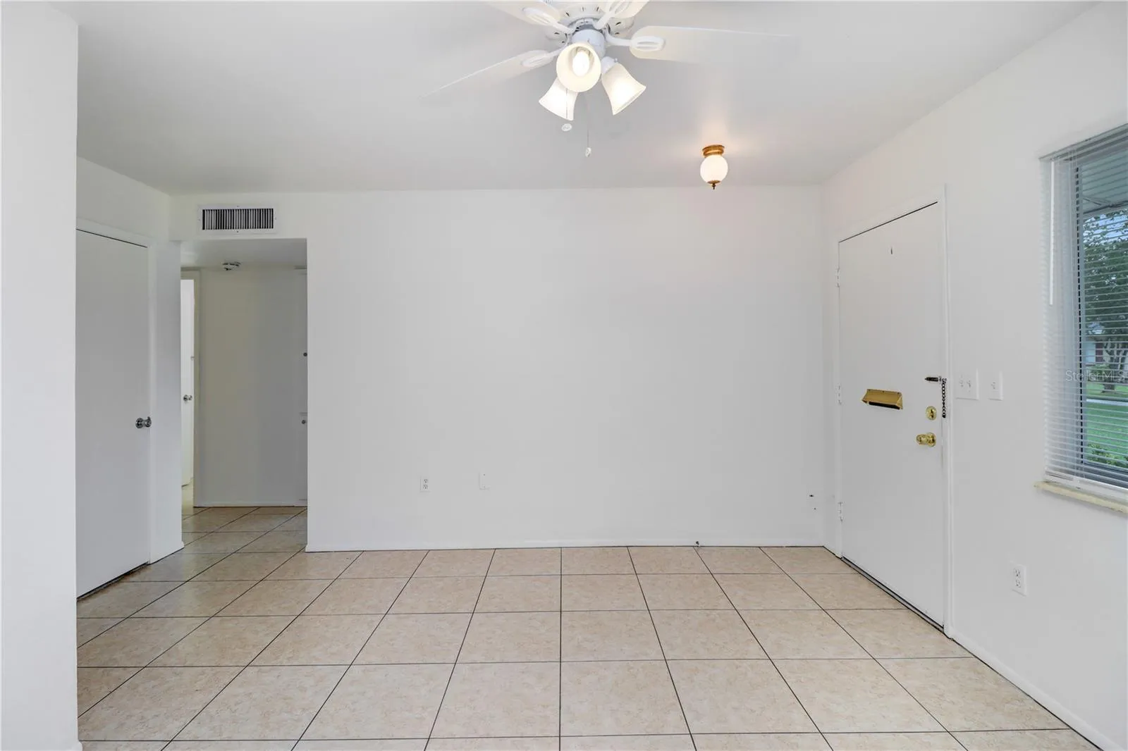 Spacious living room featuring tile flooring and a ceiling fan.