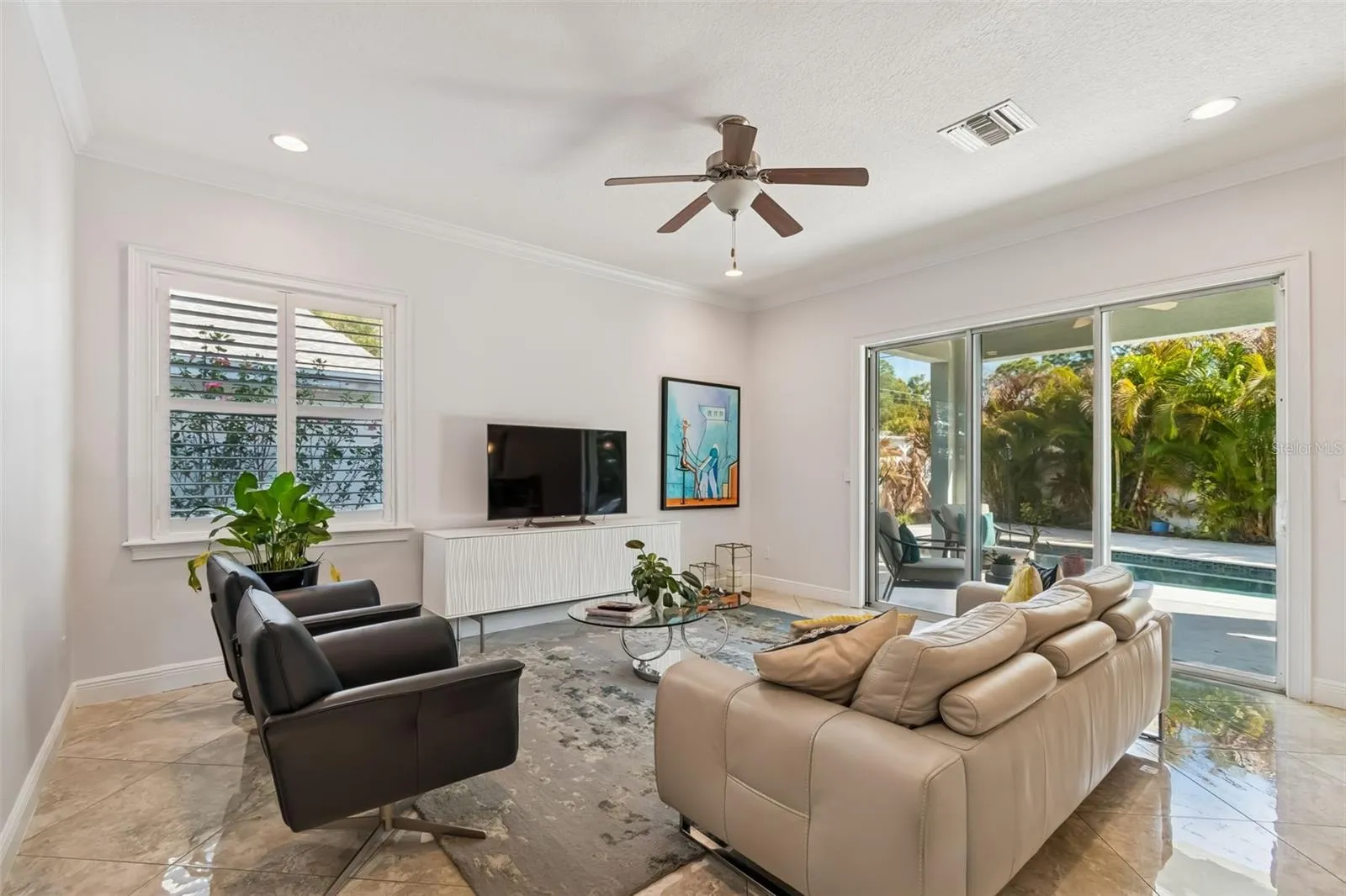 The living room opens to the backyard, connecting indoor gatherings with the poolside patio.
