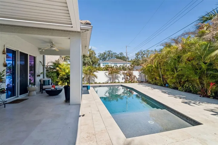 A poolside view toward the covered patio and the home’s open living area.