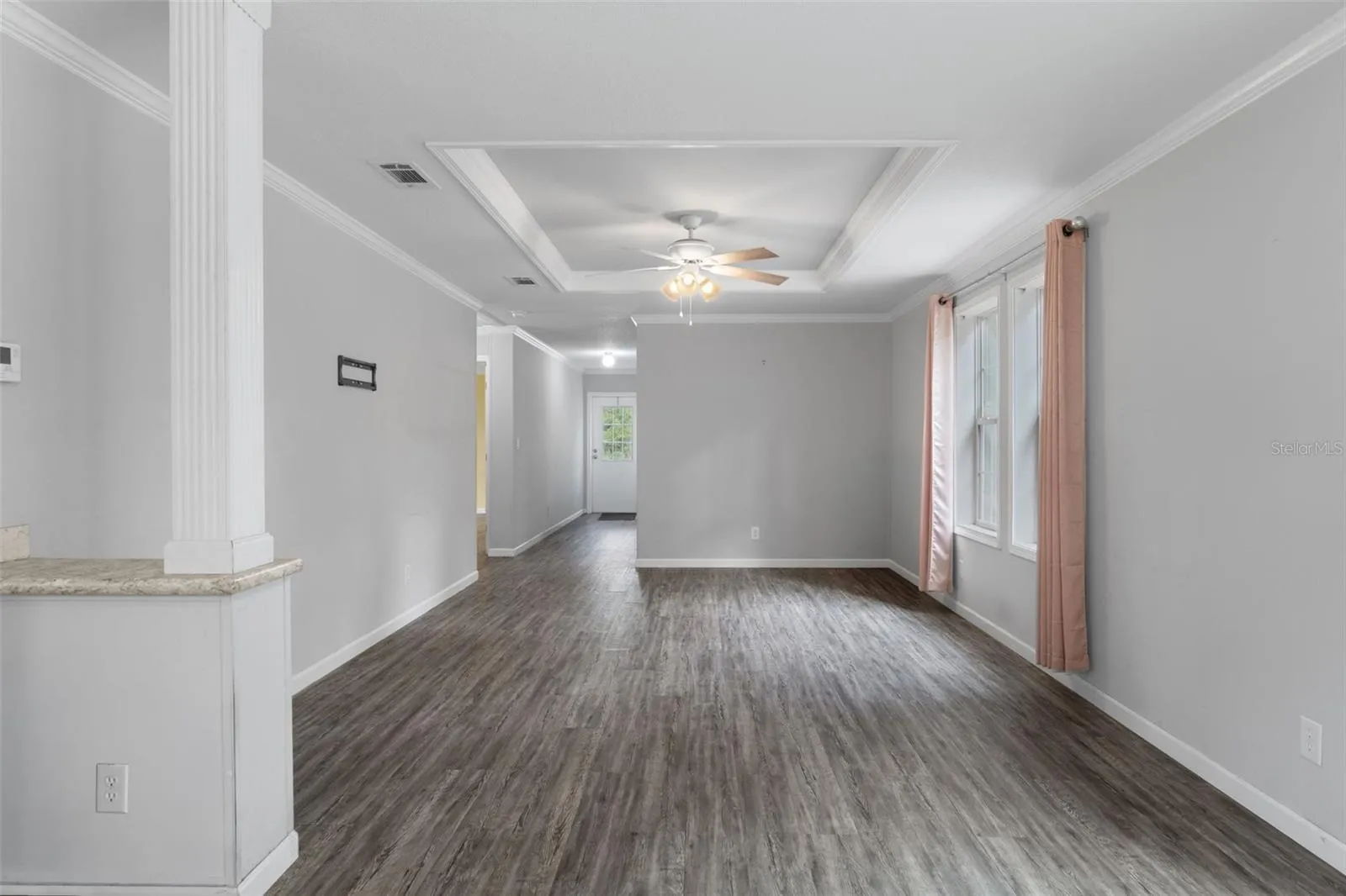 Unstaged view of the family room with LVP flooring, tray ceiling and accent column.