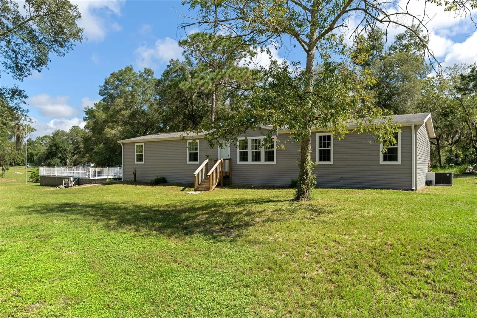 A different perspective of the home, pool and spacious property settings.
