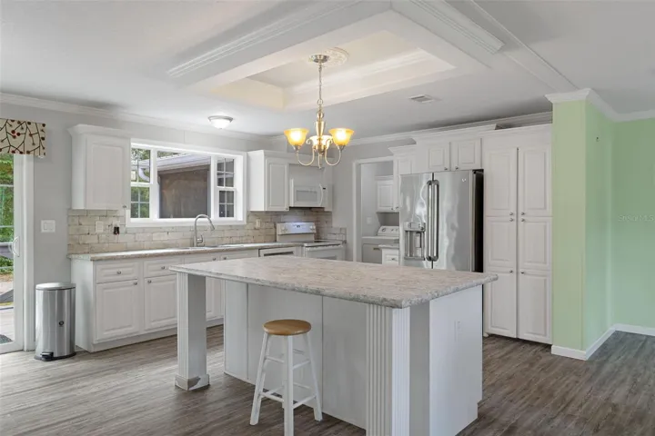Spacious kitchen with large island, hard-surface countertops, tile backsplash and abundant storage.