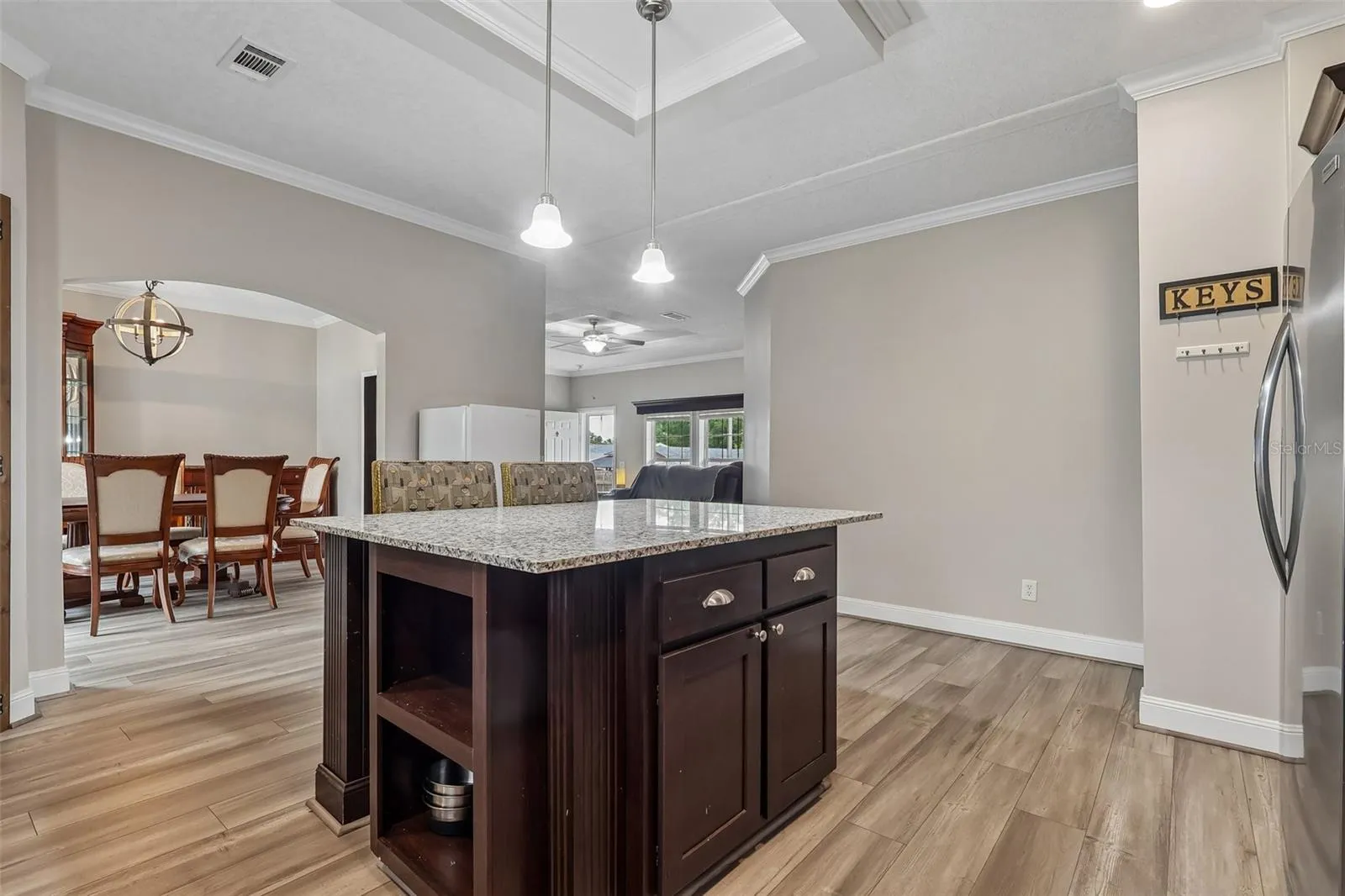 The nearby Kitchen is designed for everyday functionality and entertaining, featuring a tray ceiling, STAINLESS STEEL APPLIANCES, closet pantry and a generous KITCHEN ISLAND that provides additional workspace and gathering space.
