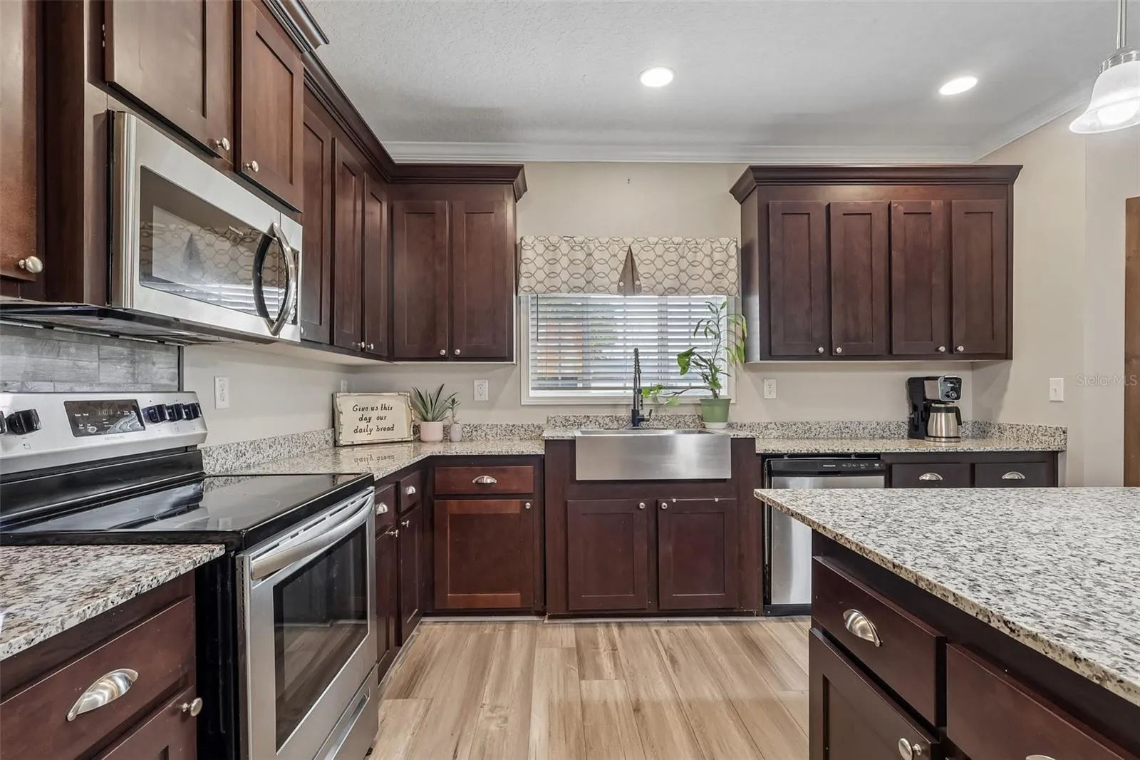 The nearby Kitchen is designed for everyday functionality and entertaining, featuring a tray ceiling, STAINLESS STEEL APPLIANCES, closet pantry and a generous KITCHEN ISLAND that provides additional workspace and gathering space.