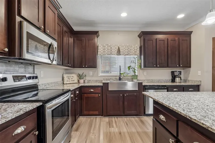 The nearby Kitchen is designed for everyday functionality and entertaining, featuring a tray ceiling, STAINLESS STEEL APPLIANCES, closet pantry and a generous KITCHEN ISLAND that provides additional workspace and gathering space.