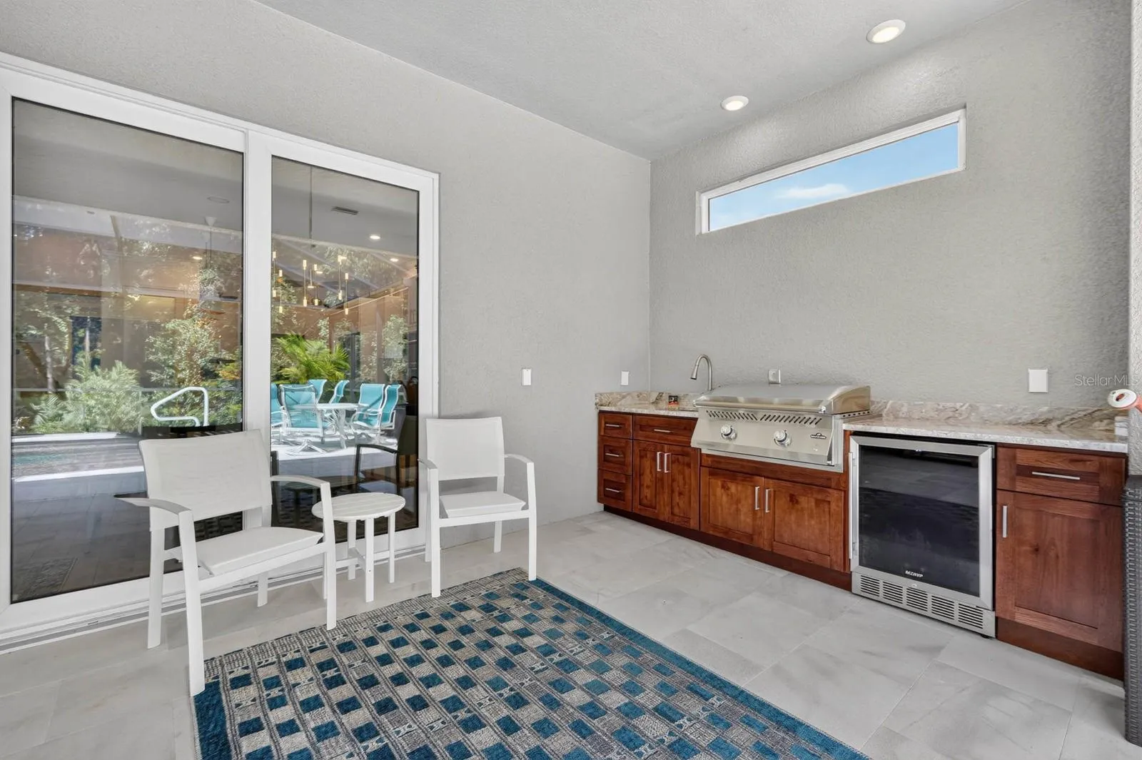 Outdoor kitchen features beautiful soft close cabinetry, granite counters and outdoor fridge and grill plus sink