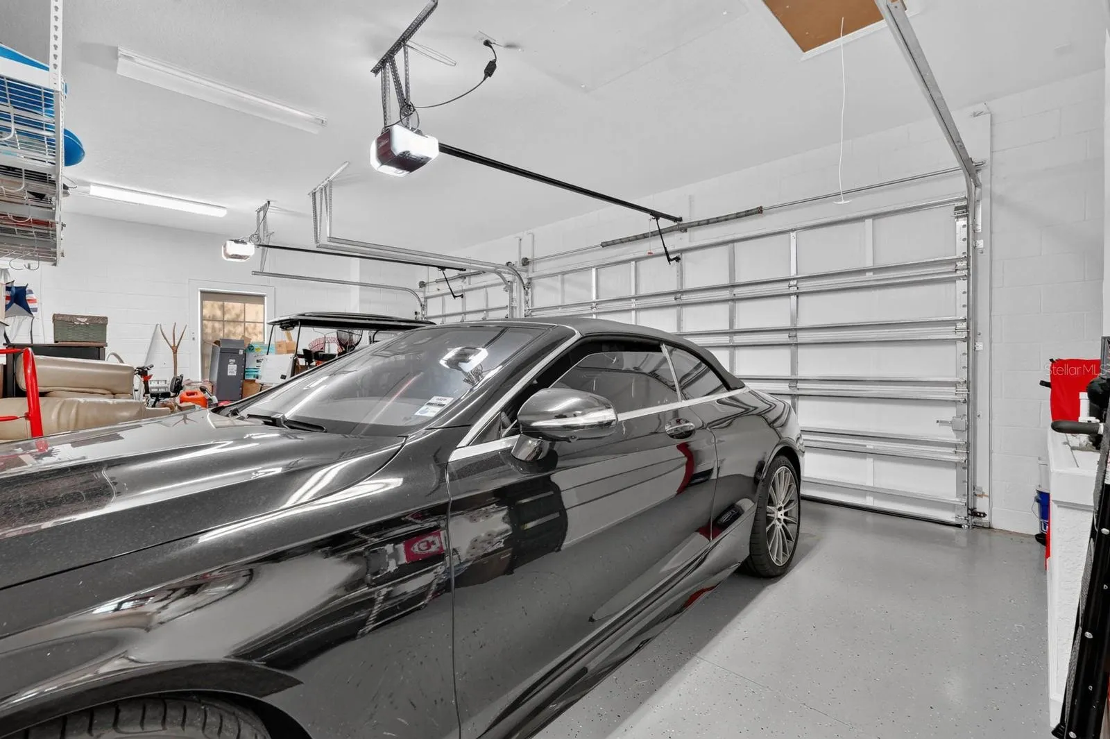 3 car garage with coated painted floor, electronic storage lift for attic and additional storage shelving.
