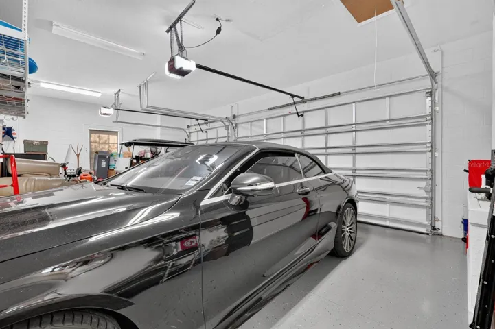 3 car garage with coated painted floor, electronic storage lift for attic and additional storage shelving.