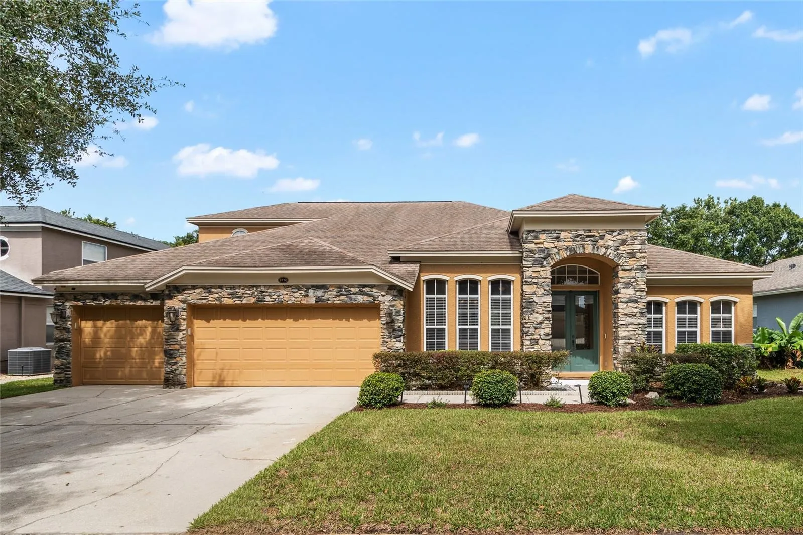 Front Elevation - 2 Story - Stone Facade with 3 Car Garage on a canopied tree lined street.
