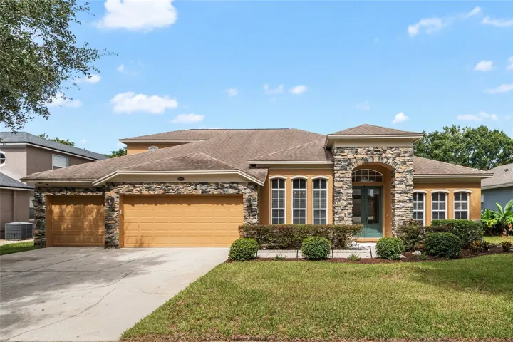 Front Elevation - 2 Story - Stone Facade with 3 Car Garage on a canopied tree lined street.