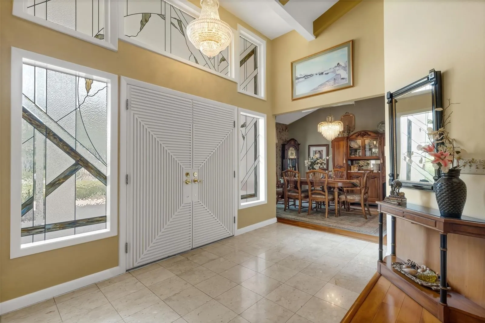 The wide double door foyer boasts easy care marble flooring and custom transom and sidelight window inserts.