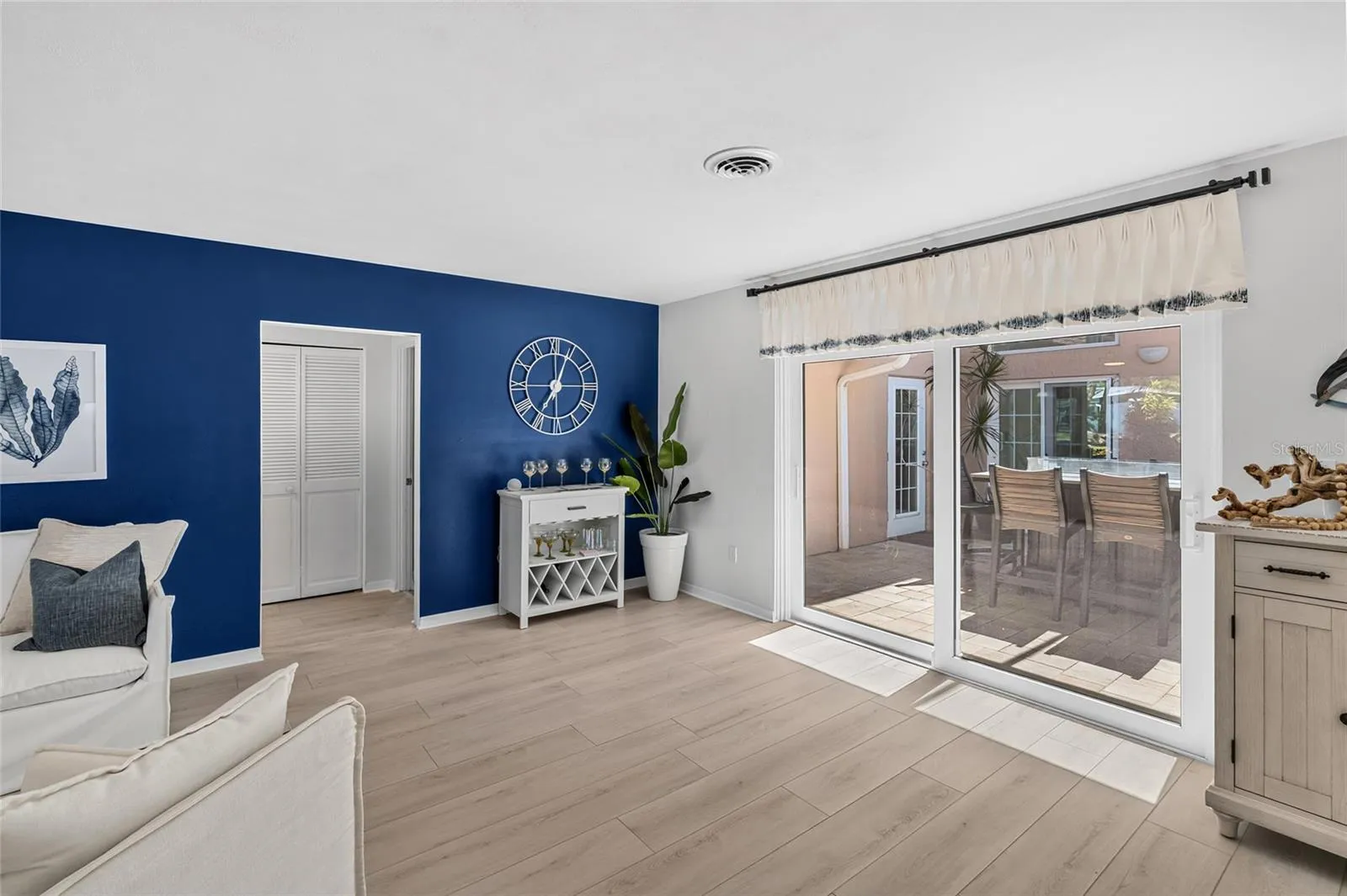 Living area opens directly to the screened courtyard lanai with tabletop fire pit and access toward the pool.