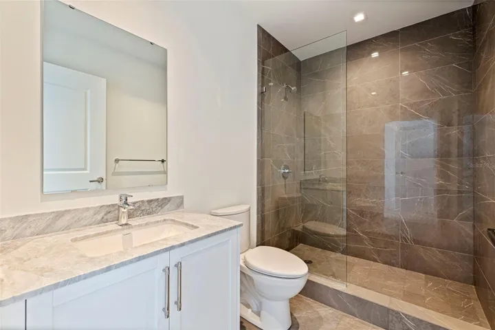 Marble finishes and a glass-enclosed shower complete the guest bath.