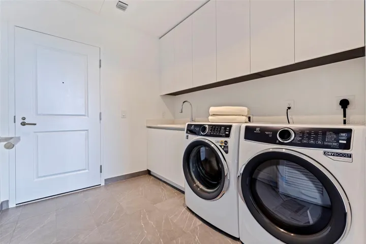 A dedicated laundry room with Electrolux washer and dryer, sink, and generous built-in storage.