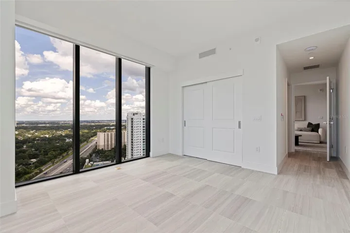 Bedroom Two sits just beyond the den, wrapped in natural light with motorized shades for privacy at a touch.
