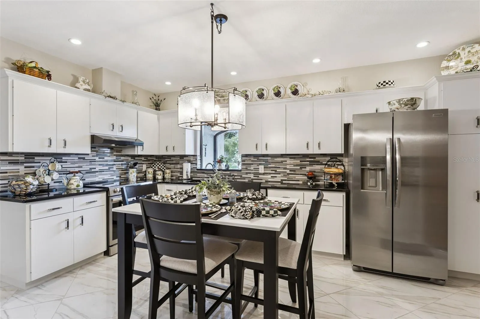 The eat-in Kitchen showcases a timeless black-and-white design, featuring crisp white cabinetry accented with crown molding