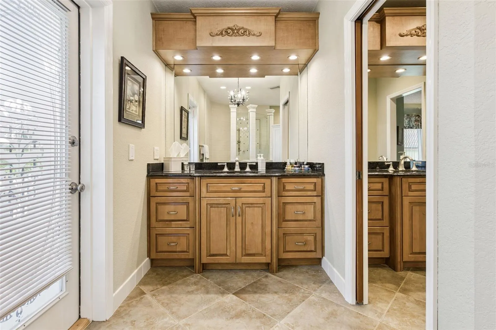 Primary Bathroom features 2 custom vanities with granite countertops and are separated by a pocket door