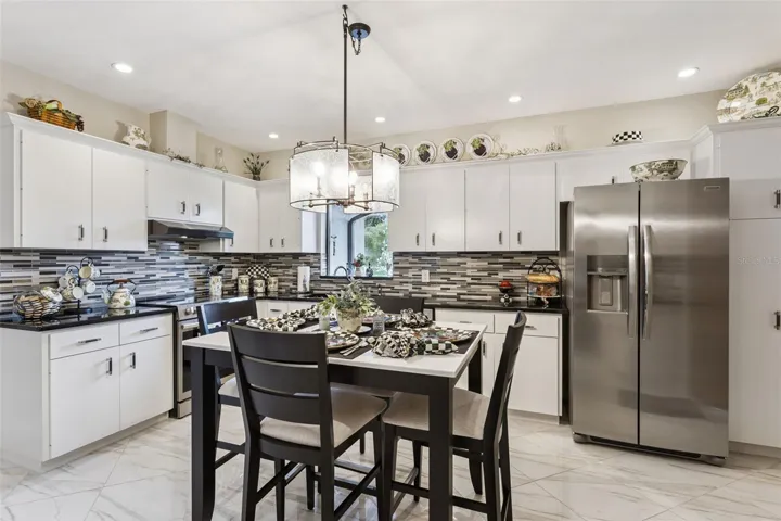 The eat-in Kitchen showcases a timeless black-and-white design, featuring crisp white cabinetry accented with crown molding