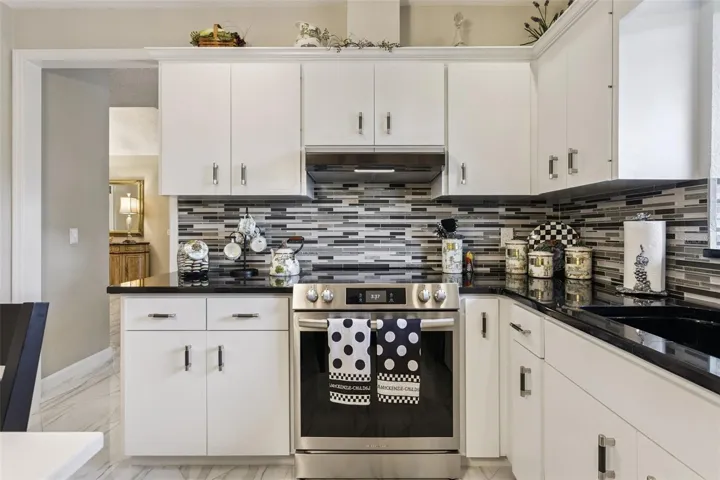 Sleek black granite countertops beautifully complement the tile backsplash and designer hardware