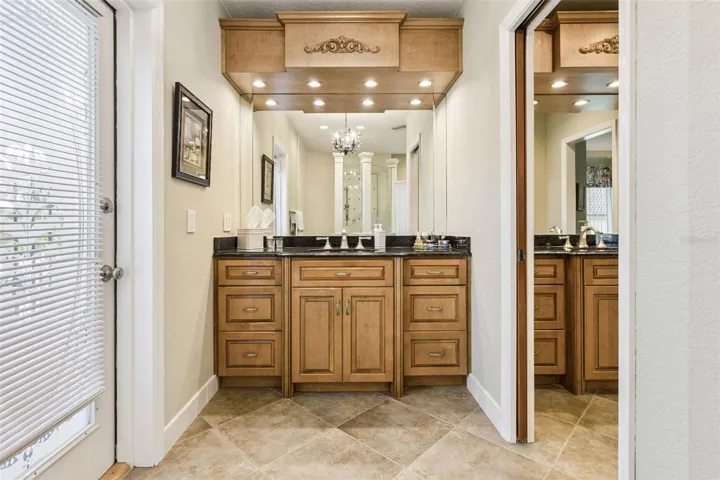 Primary Bathroom features 2 custom vanities with granite countertops and are separated by a pocket door