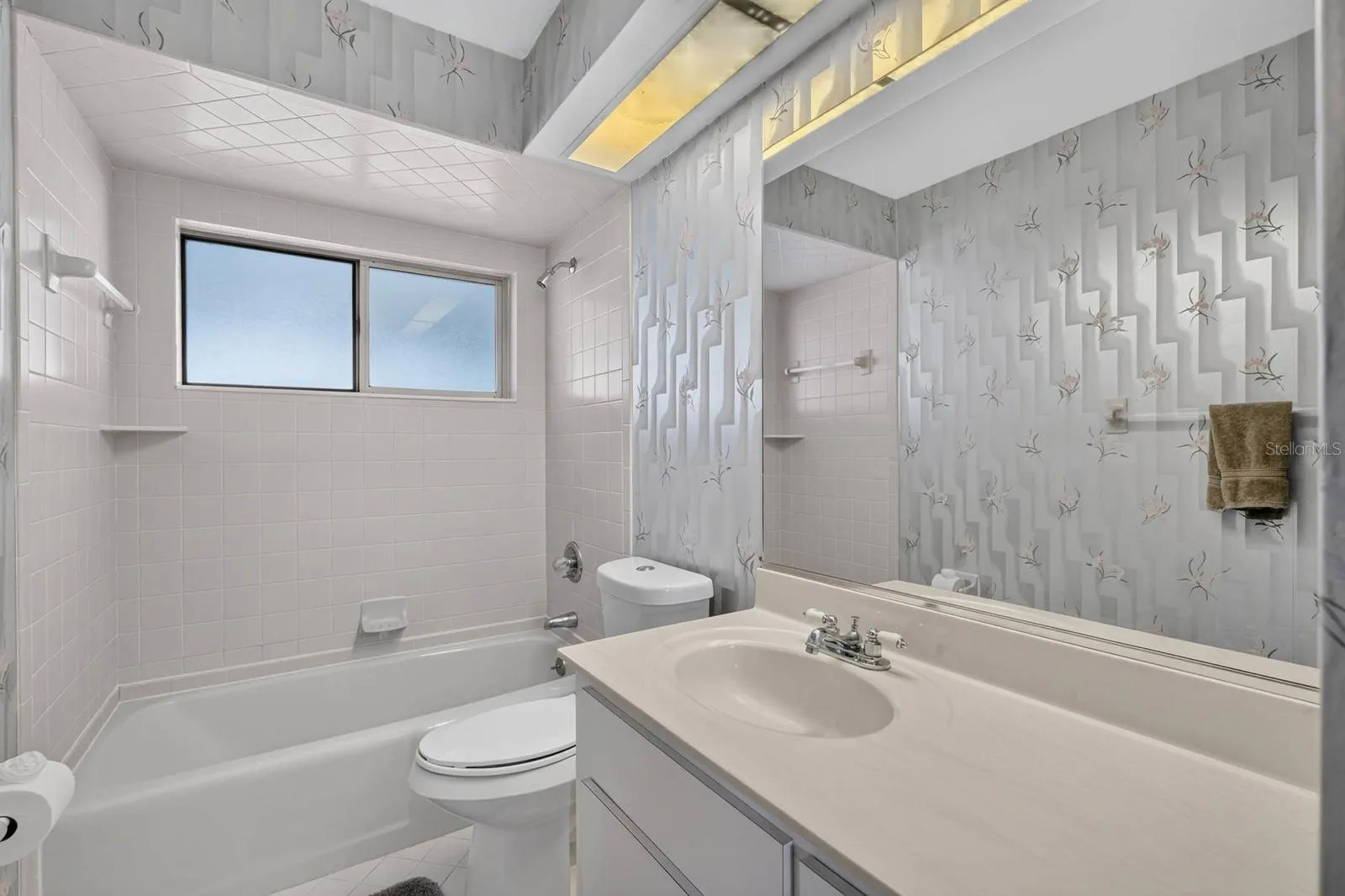 Guest bathroom features tub and tiled shower, marble countertop