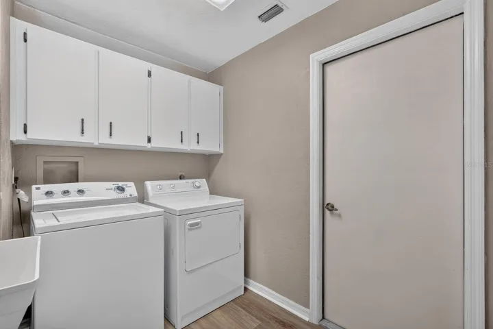 Laundry room has storage cabinetry and utility sink