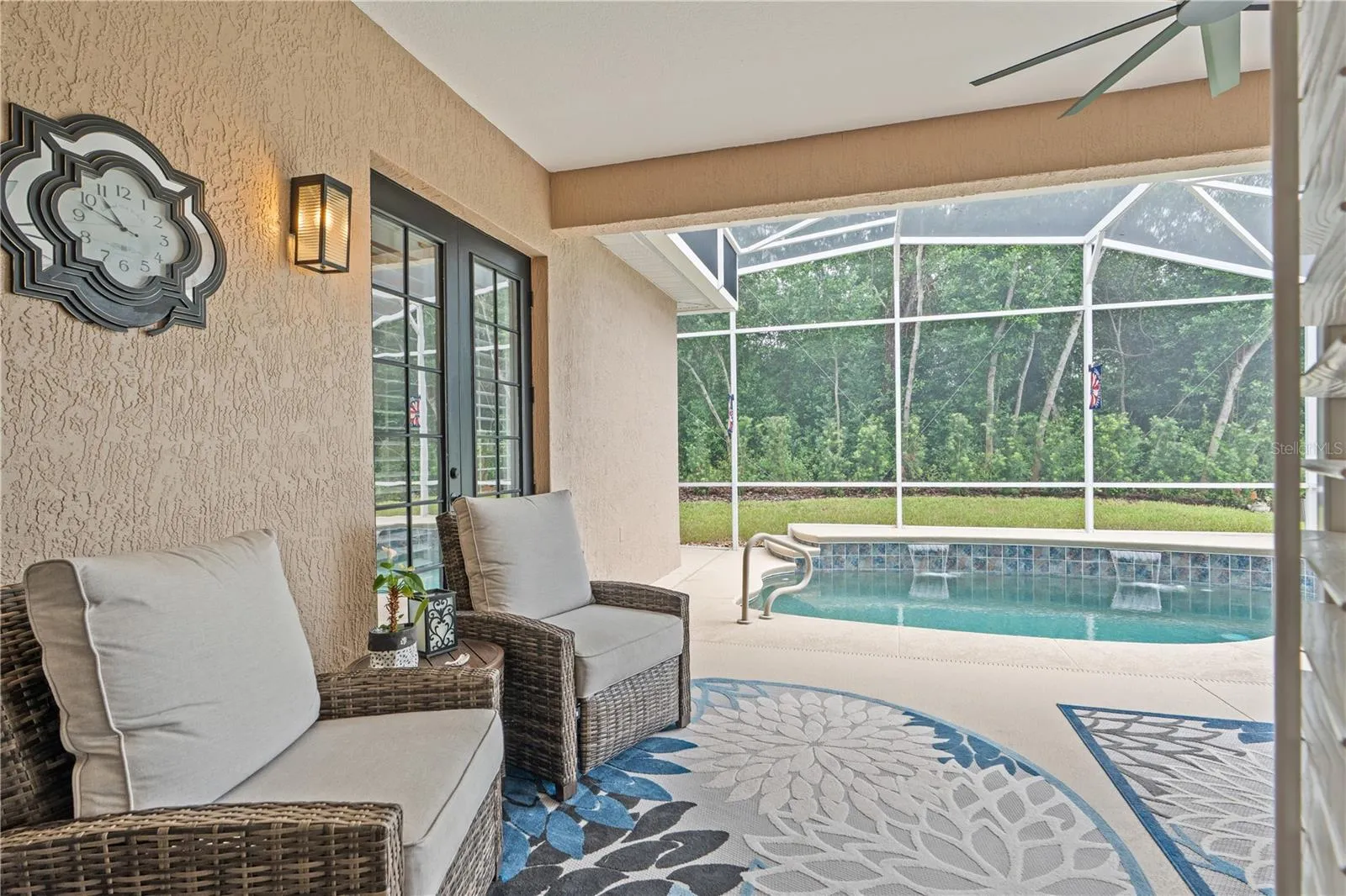 Looking out the French doors in the Great Room toward the refreshing pool -- the buffer of trees and shrubs offers privacy from the golf course just beyond