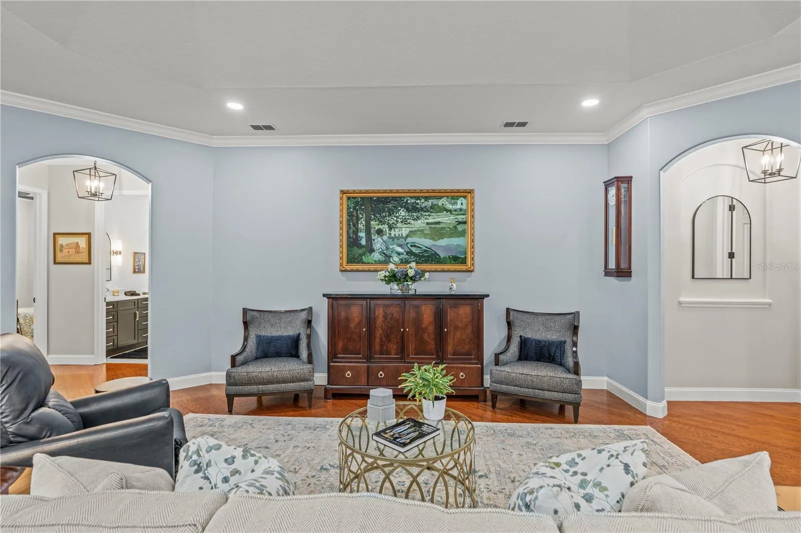 The "painting" over the cabinet is actually the TV!  The arched hallway to the right leads to the primary suite and the arched hallway to the left takes you to the 2 guest rooms and laundry room