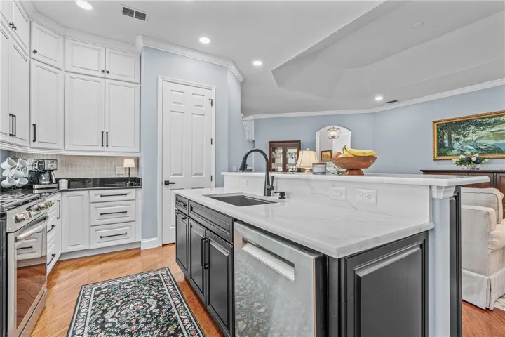 Quartz counters on the island surround a large, single bowl stainless steel sink; The door adjacent to the island is the closet pantry