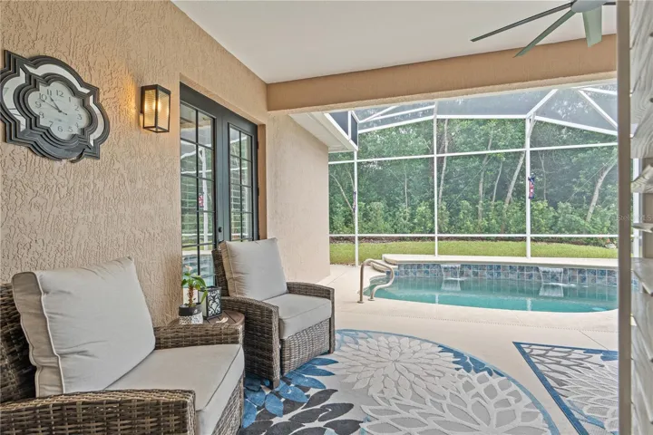 Looking out the French doors in the Great Room toward the refreshing pool -- the buffer of trees and shrubs offers privacy from the golf course just beyond