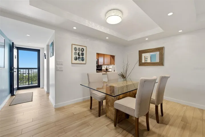 Light-filled dining area with elegant tray ceiling and recessed lighting.