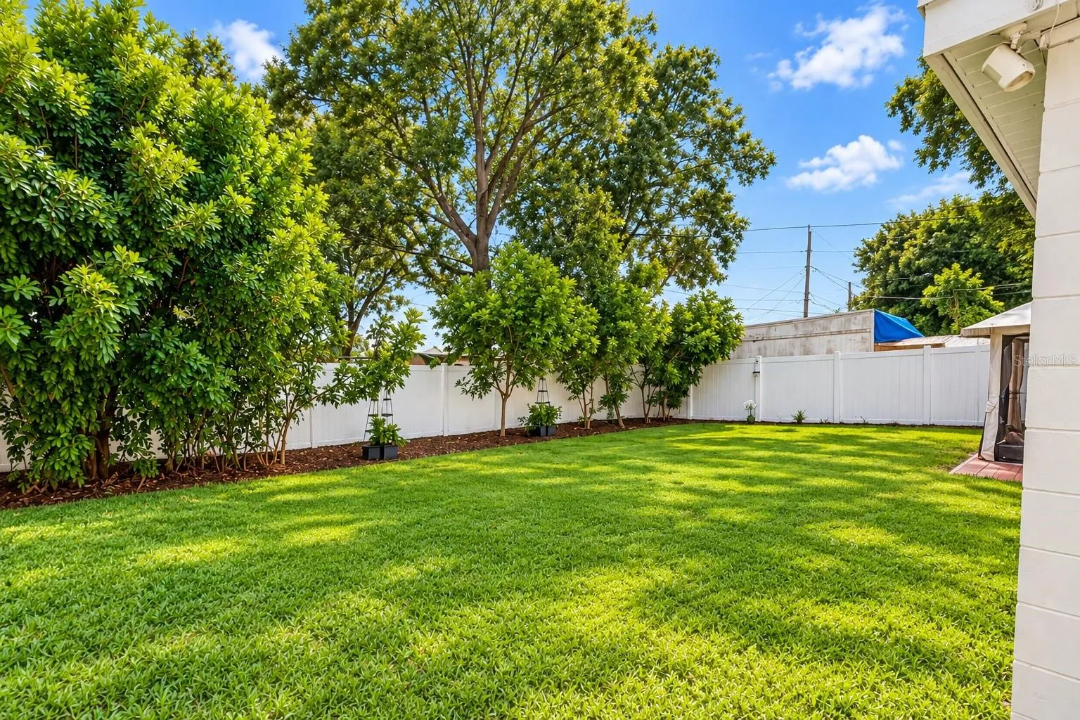 Large private backyard surrounded by white vinyl privacy fencing.