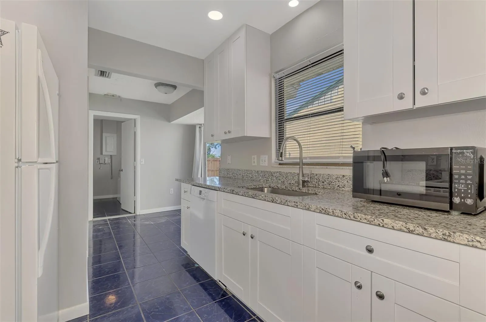 Kitchen Recently renovated with granite countertops looking towards laundry room and slider to the back fenced in yard