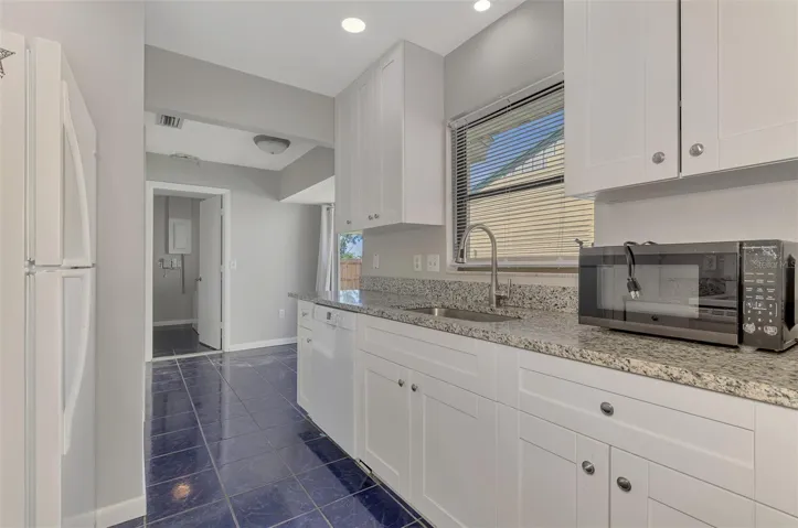 Kitchen Recently renovated with granite countertops looking towards laundry room and slider to the back fenced in yard