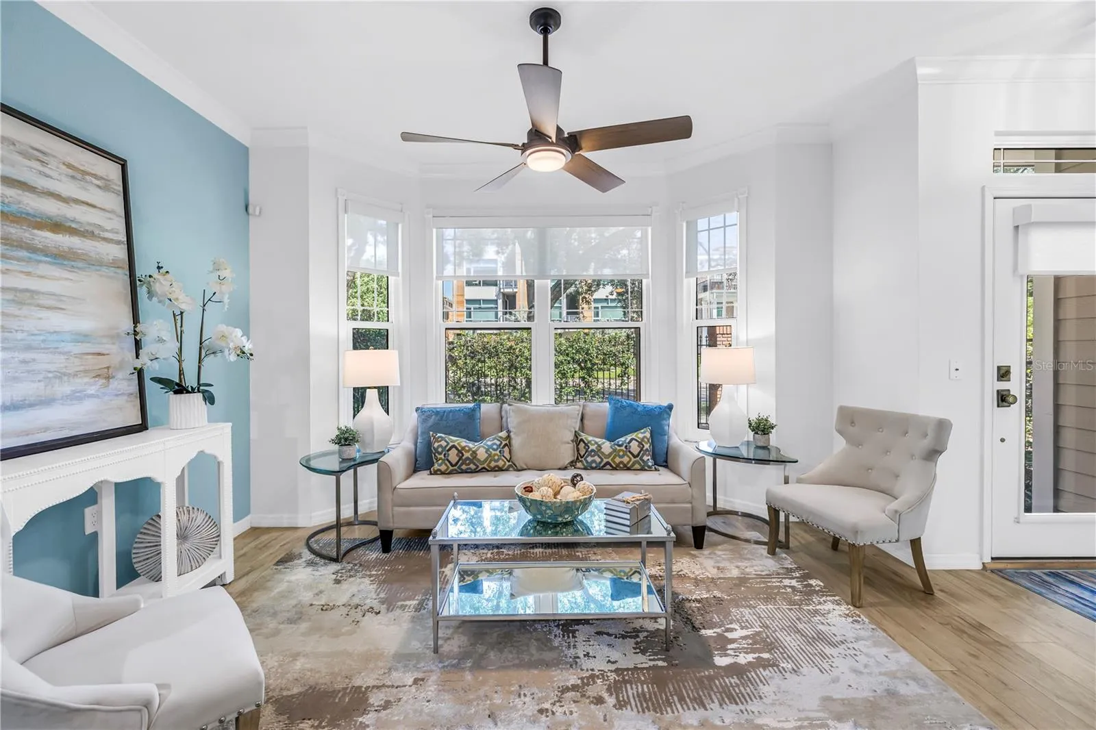 Bright and inviting living room features a bay window, luxury vinyl plank flooring and a remote-controlled sun shade.