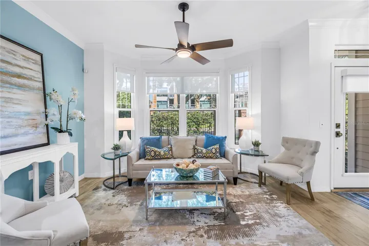 Bright and inviting living room features a bay window, luxury vinyl plank flooring and a remote-controlled sun shade.