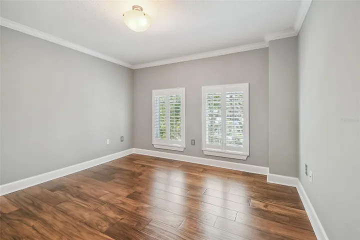 Guest bedroom, featuring hardwood floors and plantation shutters.