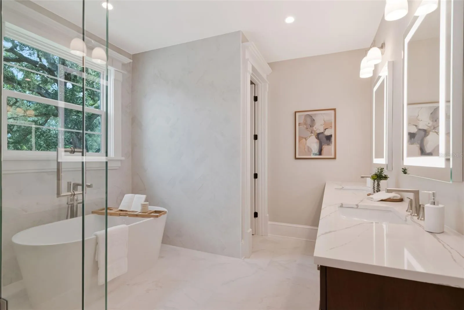 Dual vanities, glass shower, and tub in primary bath