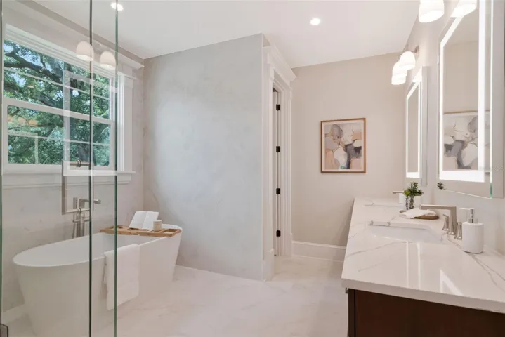 Dual vanities, glass shower, and tub in primary bath