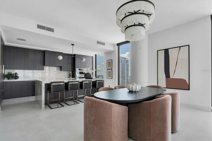 Designer dining area framing quartz waterfall island.